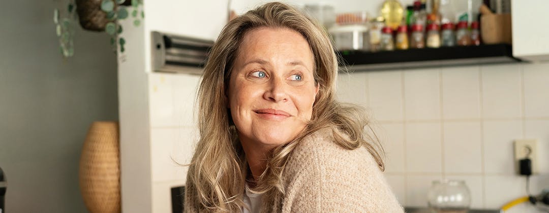 Smiling woman with blonde hair standing against a tiled wall background